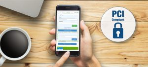 Hand holding smartphone with login screen, coffee and PCI compliance logo