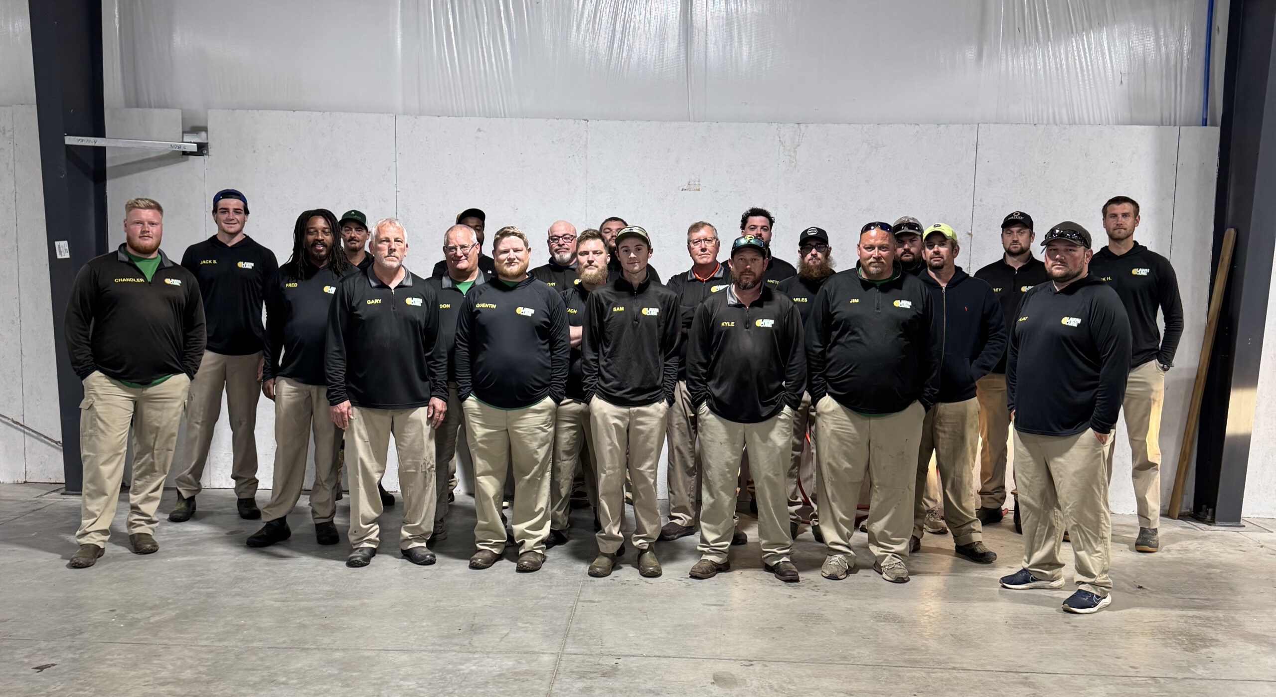 Group of workers in black shirts and khaki pants posing together