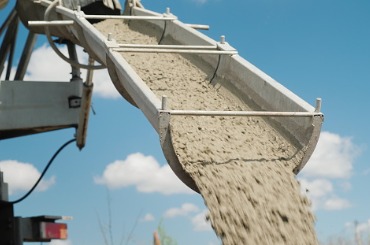 Sand or gravel pouring from conveyor chute against blue sky