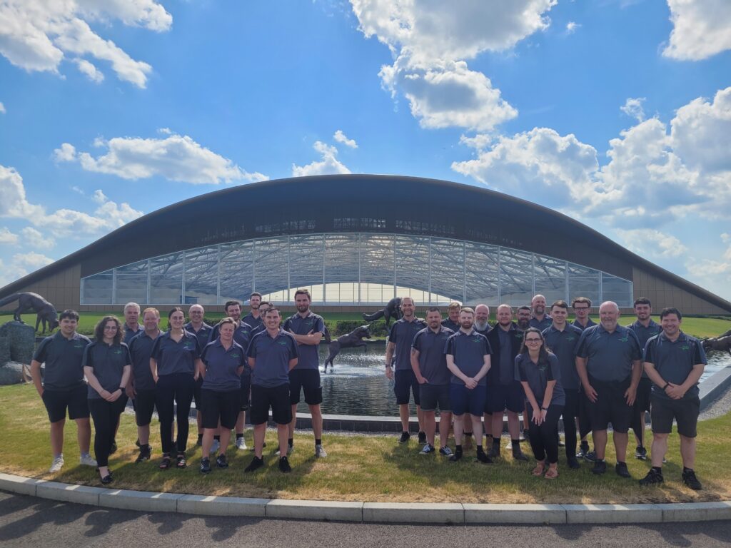 Group of staff in matching uniforms pose in front of modern curved building