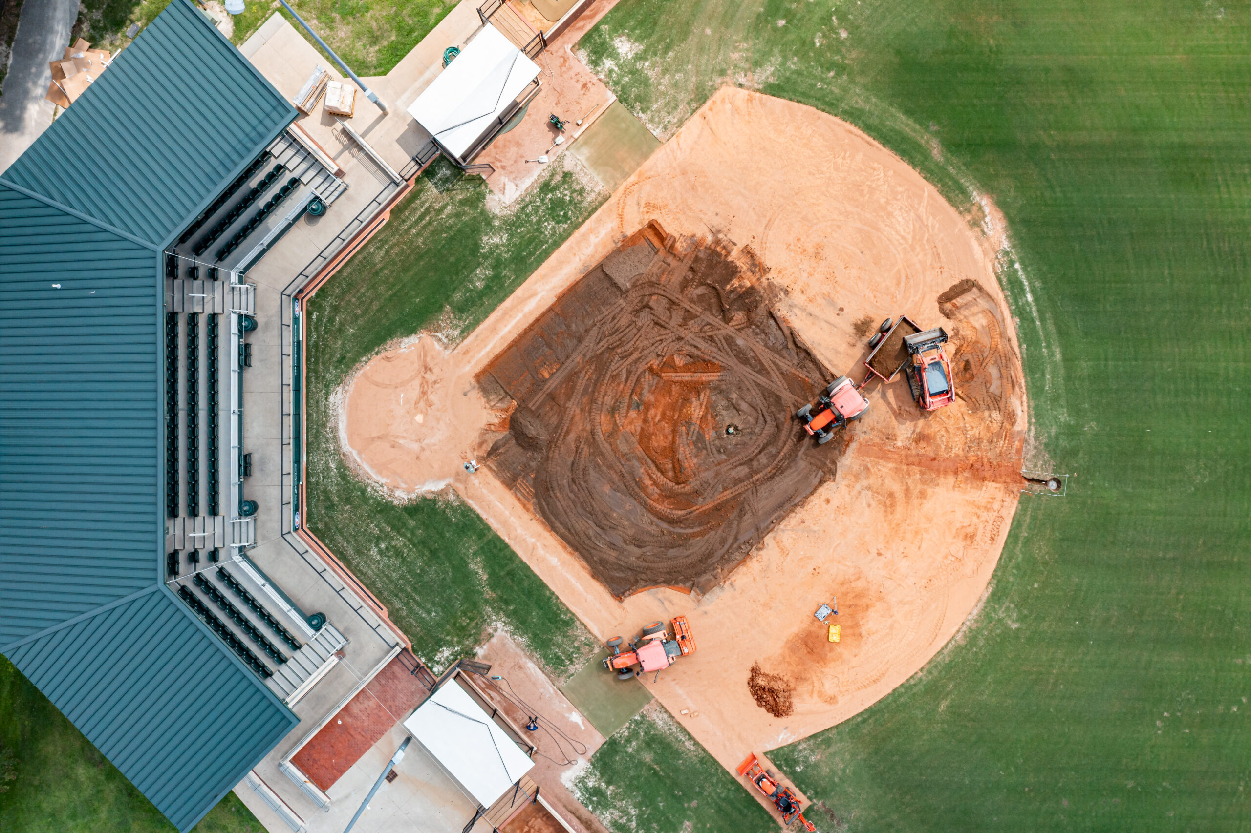 Aerial view of baseball field construction with tractors and dirt