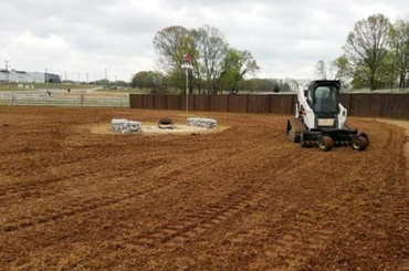 Skid steer leveling soil on a brown construction or landscaping site