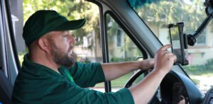 Driver in green cap and shirt concentrating while steering delivery van