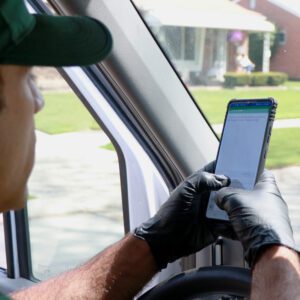 Driver wearing gloves checks smartphone while sitting in vehicle