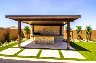 Modern outdoor patio with pergola, kitchen, and landscaped green lawn