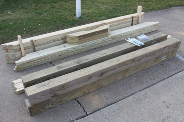 Stacked wooden lumber planks on concrete surface near grass