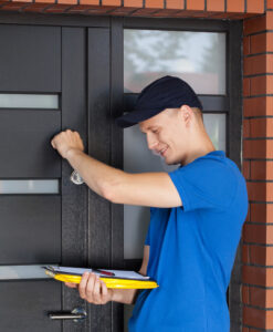 Person in blue shirt measuring door frame with yellow measuring tape