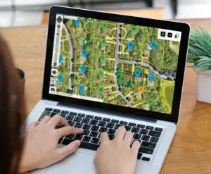 Person using laptop with digital map showing urban landscape and green spaces