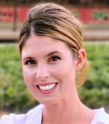 Smiling professional woman with blonde hair outdoors in garden setting