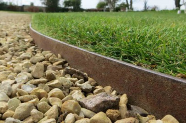 Curved border separating smooth green grass from rough stone pathway