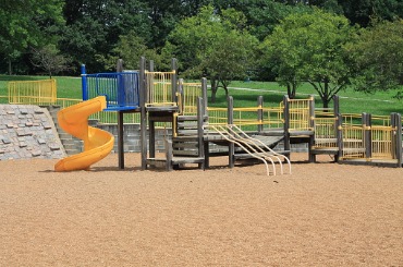Colorful empty playground with yellow and blue slides on sandy ground