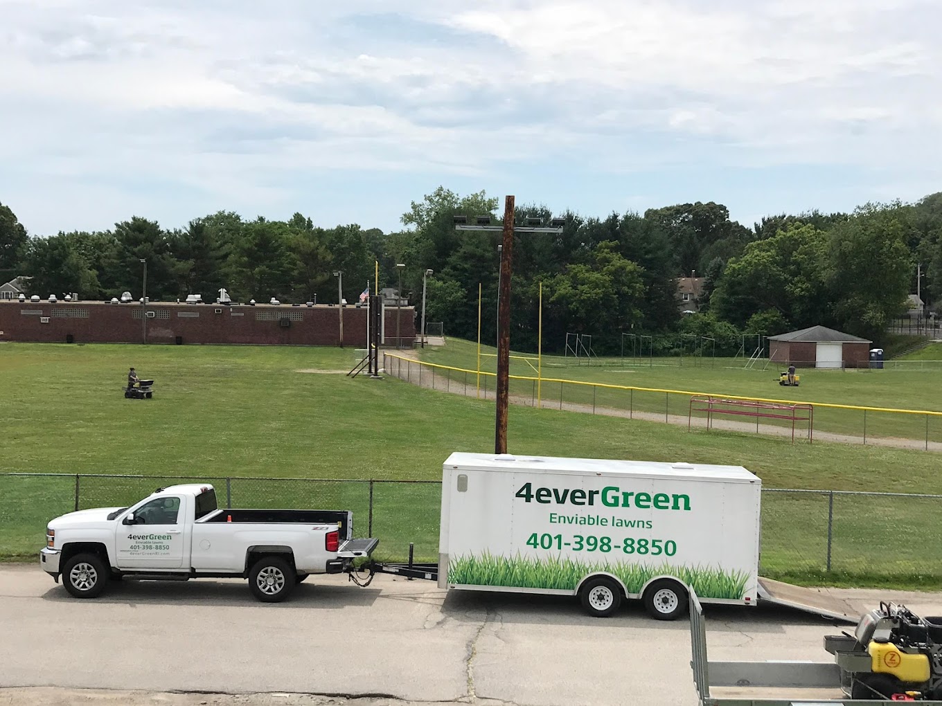 4everGreen truck and trailer parked near sports field with lawn equipment