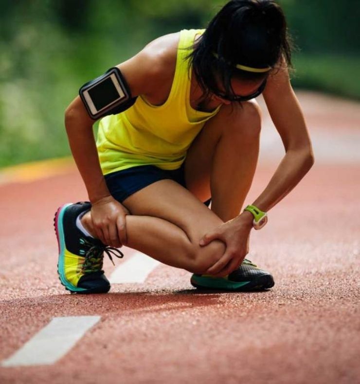 Runner bent over with a knee and ankle injury