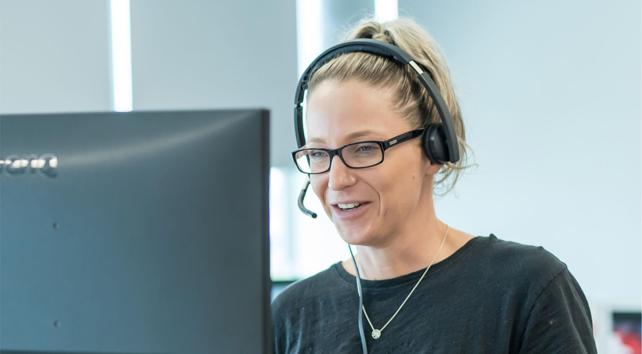 A person wearing a headset sitting behind a computer