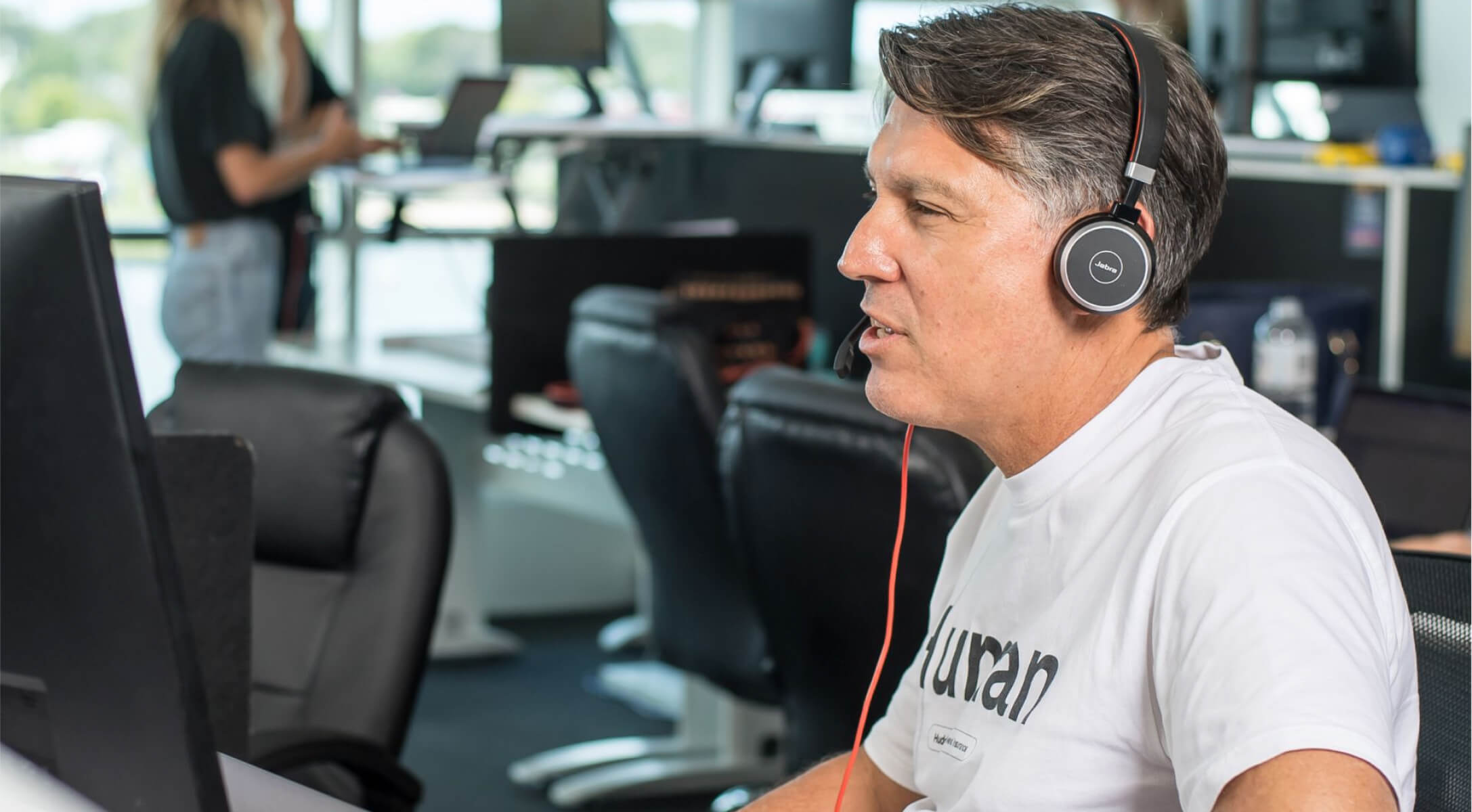 A person wearing a headset behind a computer