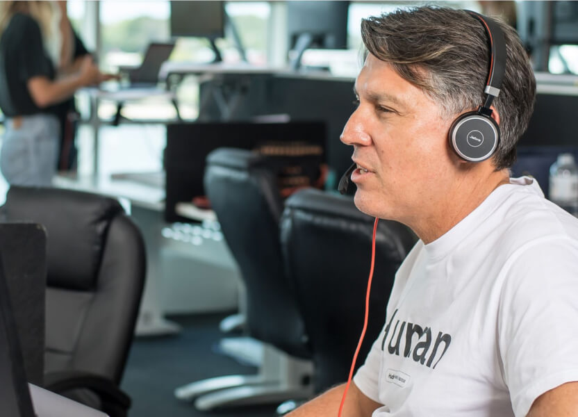 A person wearing a headset behind a computer