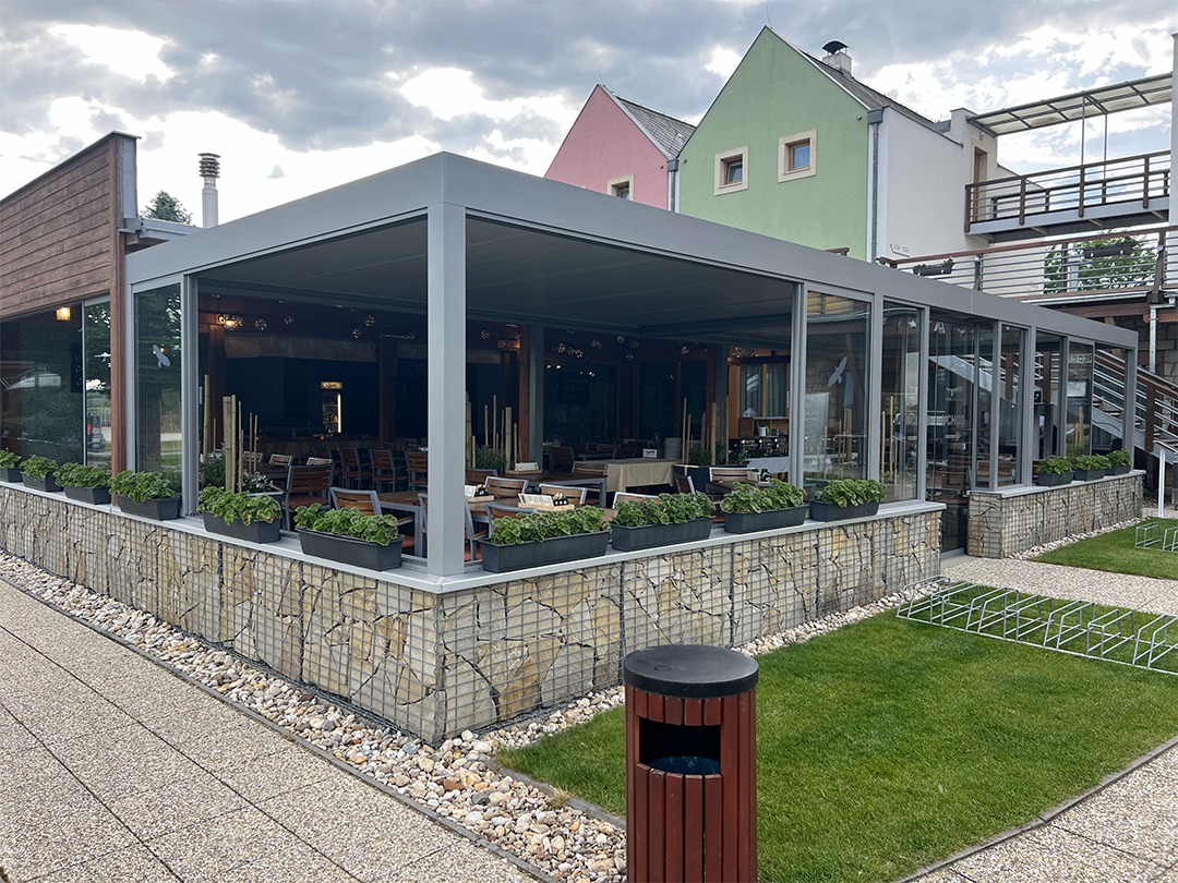 Květináče s rostlinami kolem terasy s moderní bioklimatickou pergolou