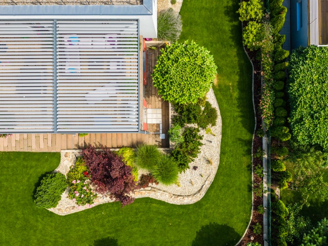 Okrasný záhon s rostlinami v blízkosti terasy s bioklimatickou pergolou