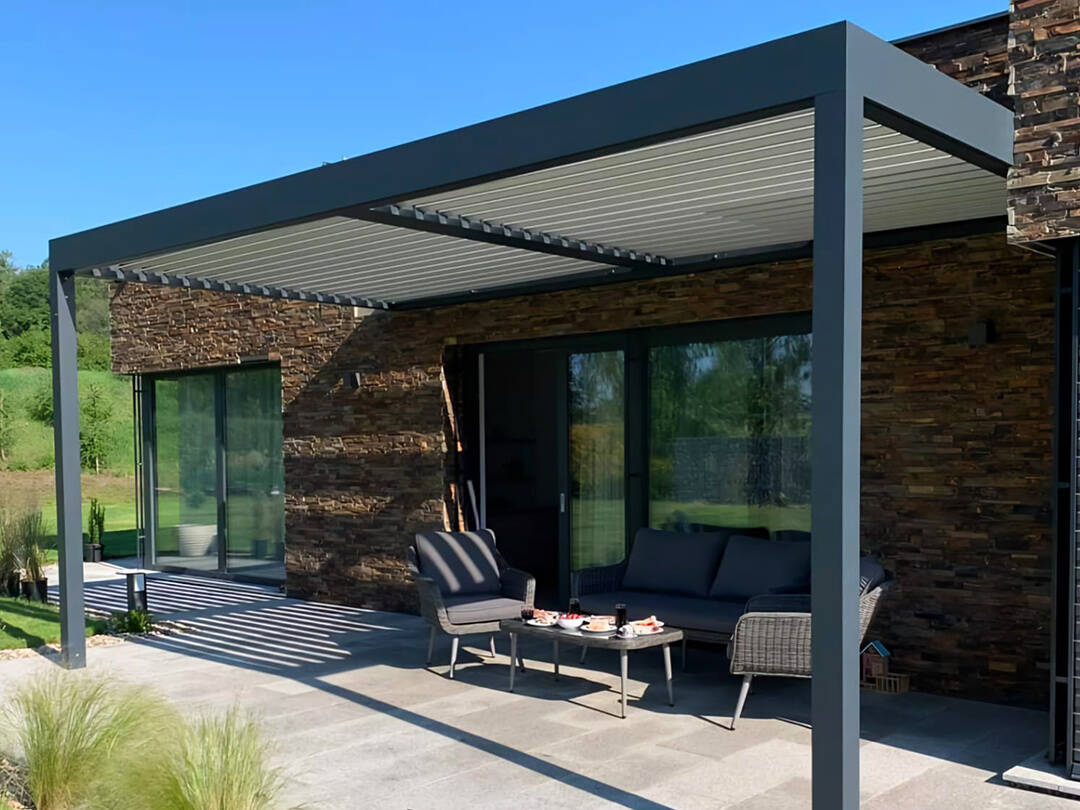Antracitová bioklimatická pergola ukotvená do kamennej fasády
