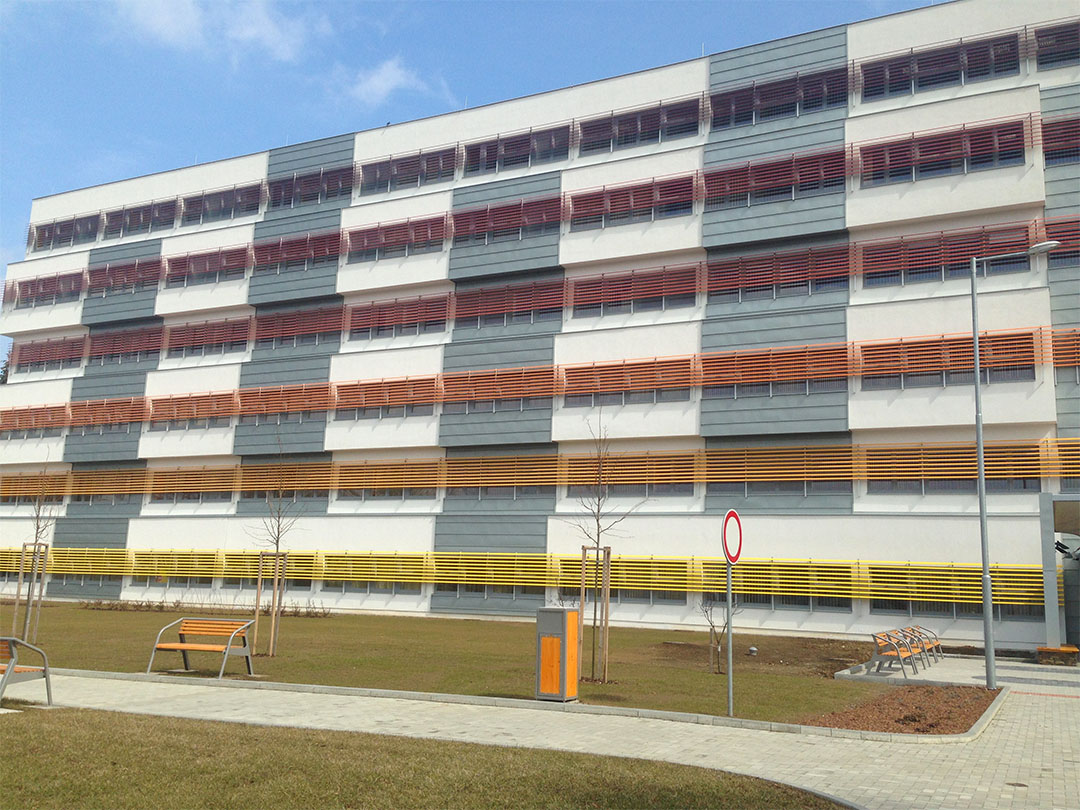 Barevná fasáda veřejné budovy s horizontálními slunolamy nad okny