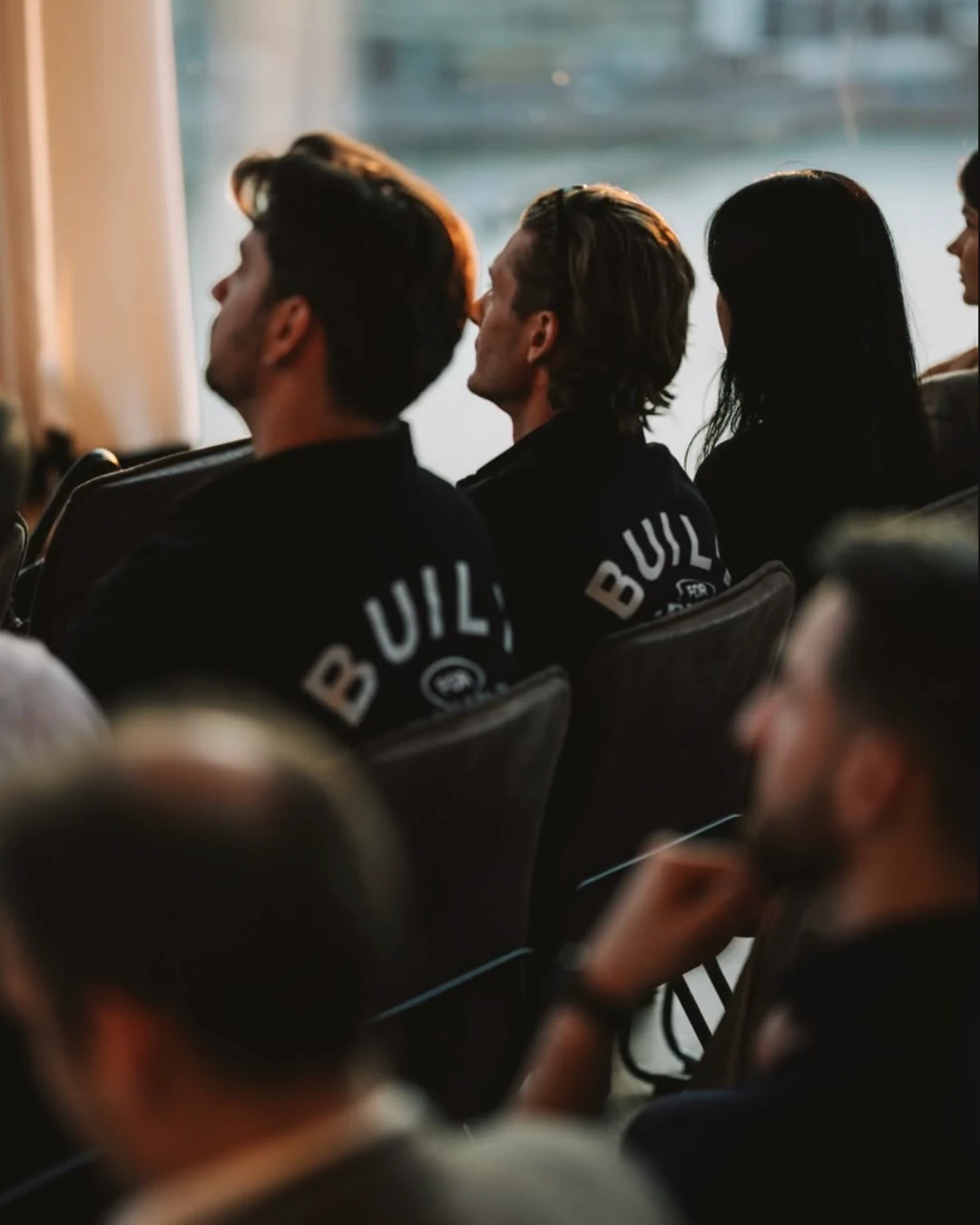 Alt: Publiek tijdens het Qonto-event in The Loft, met een spreker op het podium en de Qonto-tagline zichtbaar op het raam