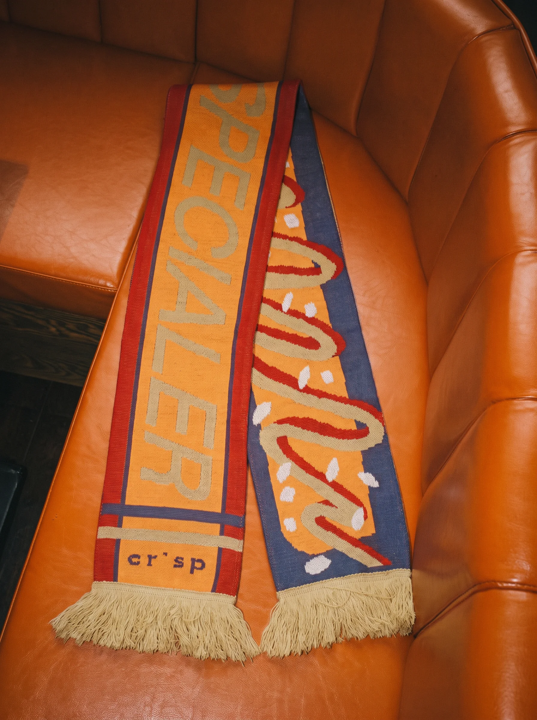 Gebreide sjaal in oranje en blauw met Specialer en crisp logo