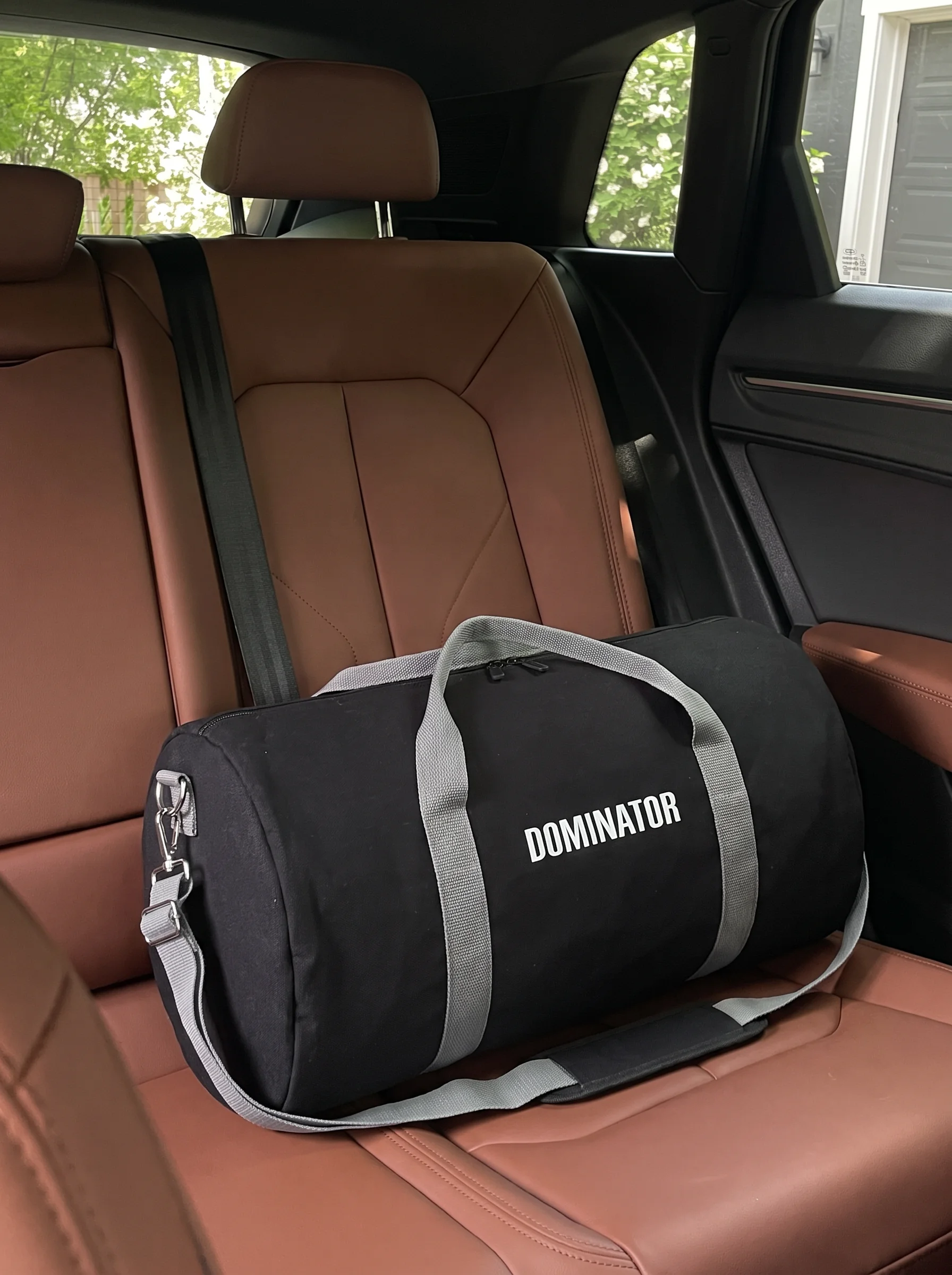 Zwarte duffel tas bedrukt met Dominator-logo op de autobank
