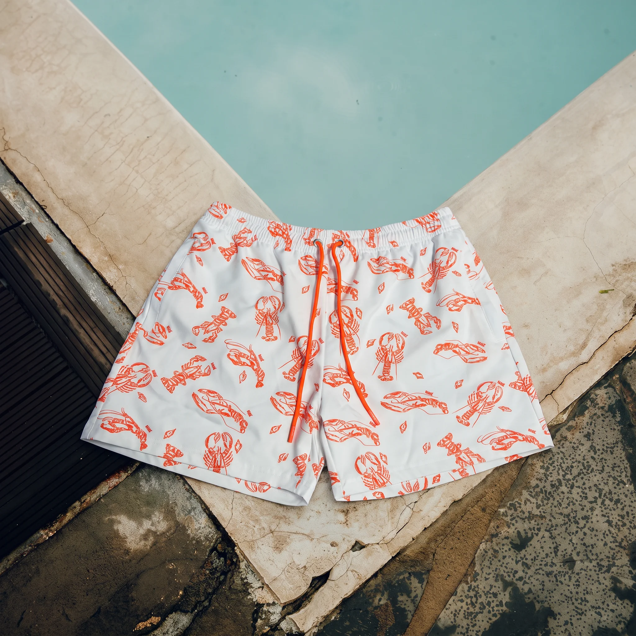Witte zwembroek met oranje kreeftenprint aan het zwembad