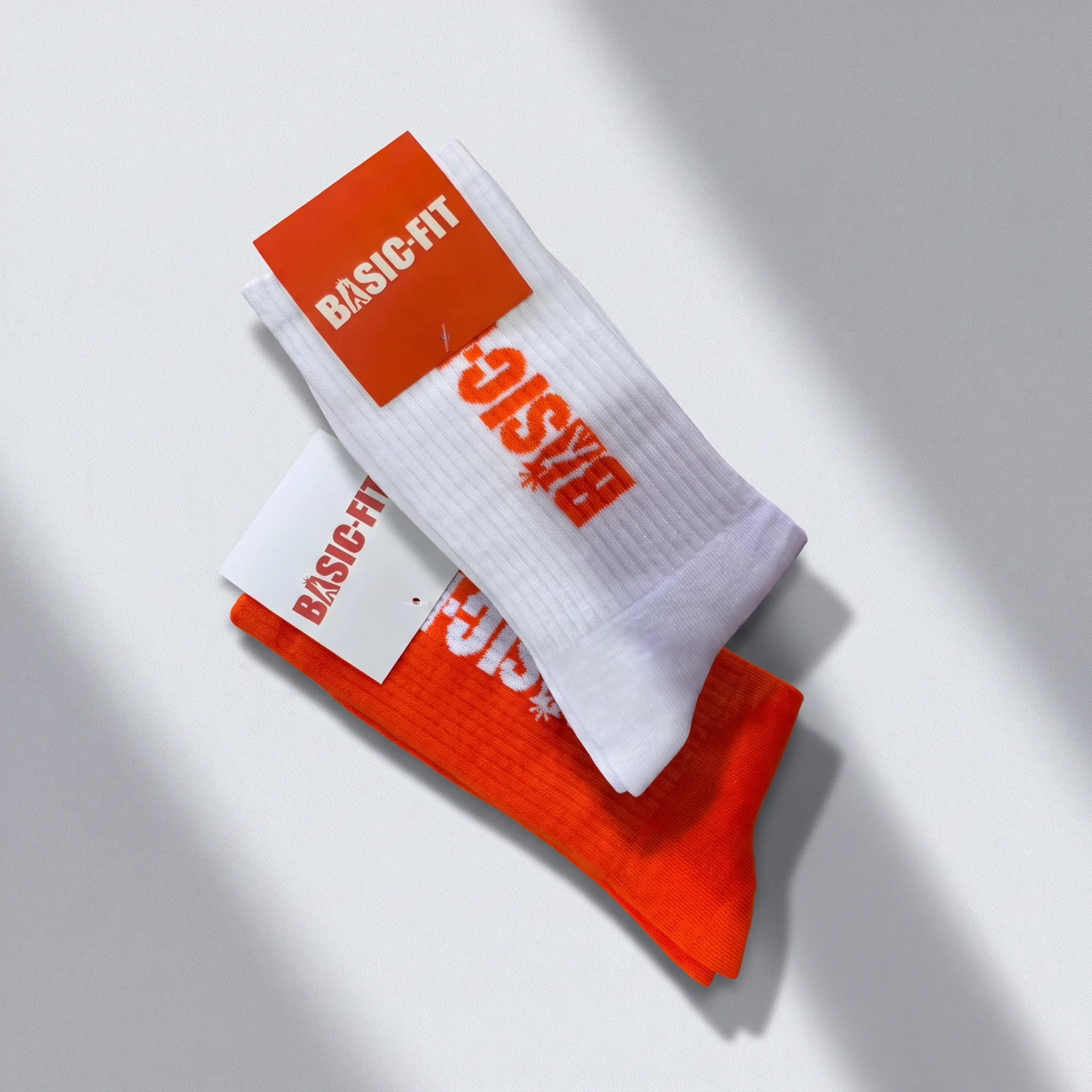 Witte en oranje sokken bedrukt met Basic-Fit logo en hangtag