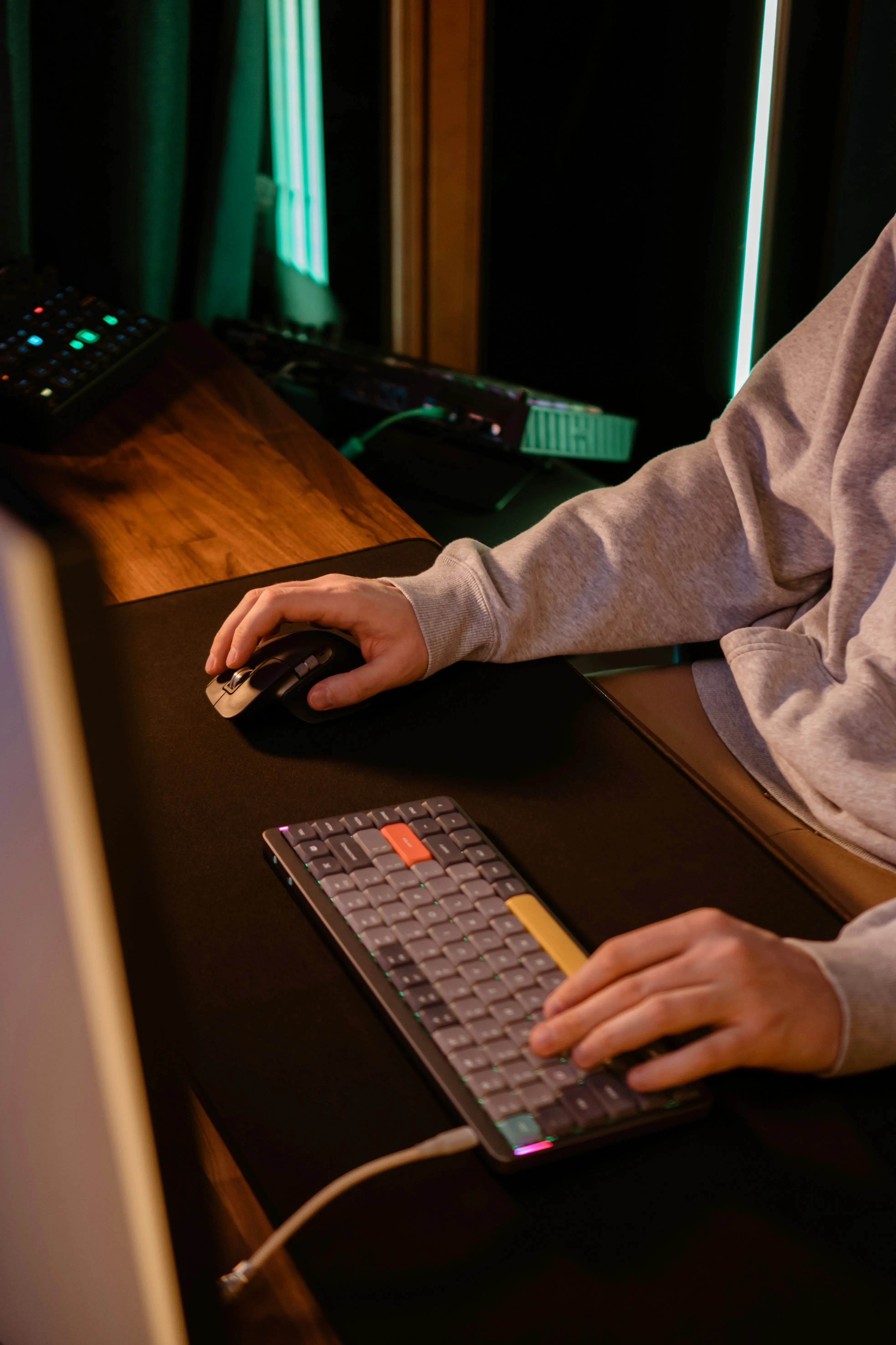 Person using computer with keyboard and mouse in dimly lit room