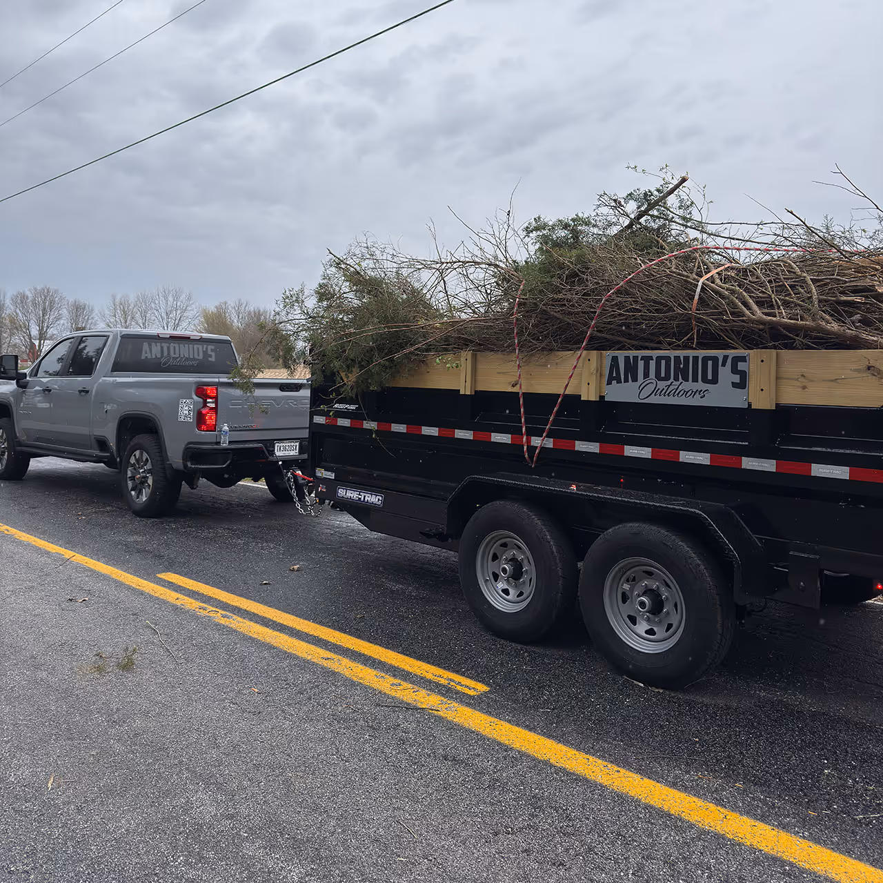 Antonio’s Outdoors hauling brush and yard debris with a commercial dump trailer for efficient residential property cleanup.