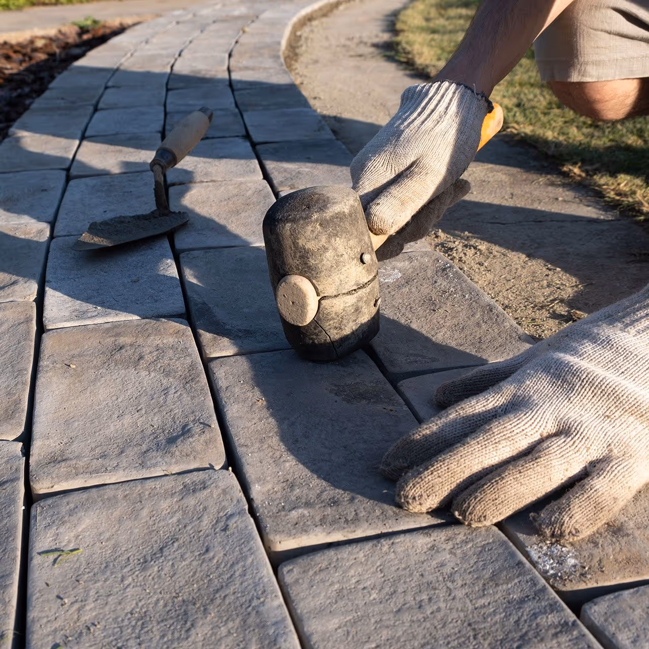 Worker installing newly cut stone walkway pavers for a clean look near me.