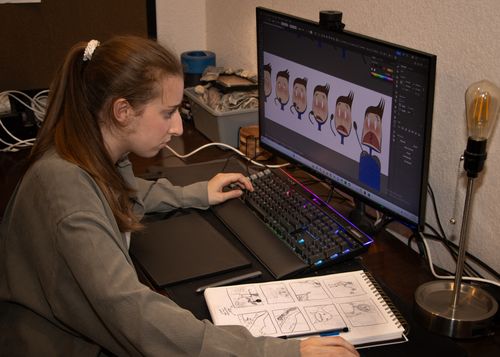 Karly sitting at a computer working on graphics for an animation