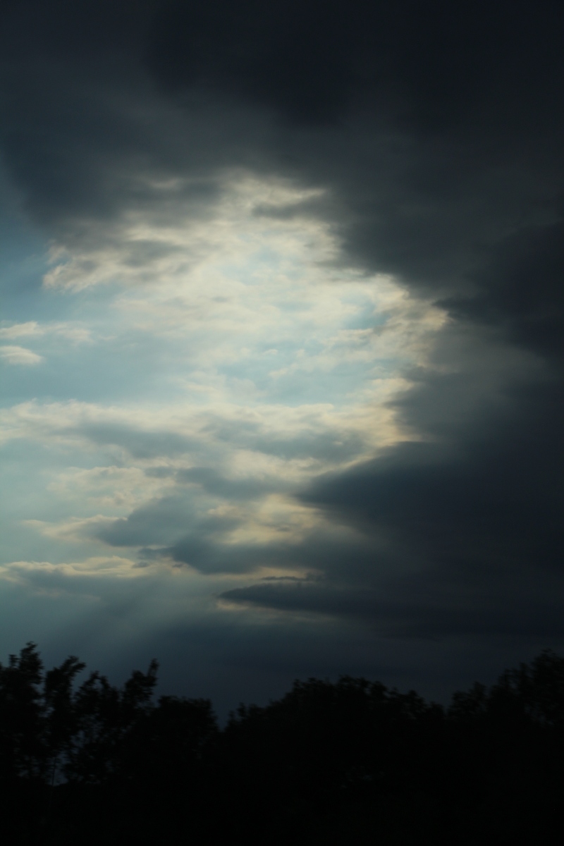 A section of clouds letting in light while the rest of sky is dark