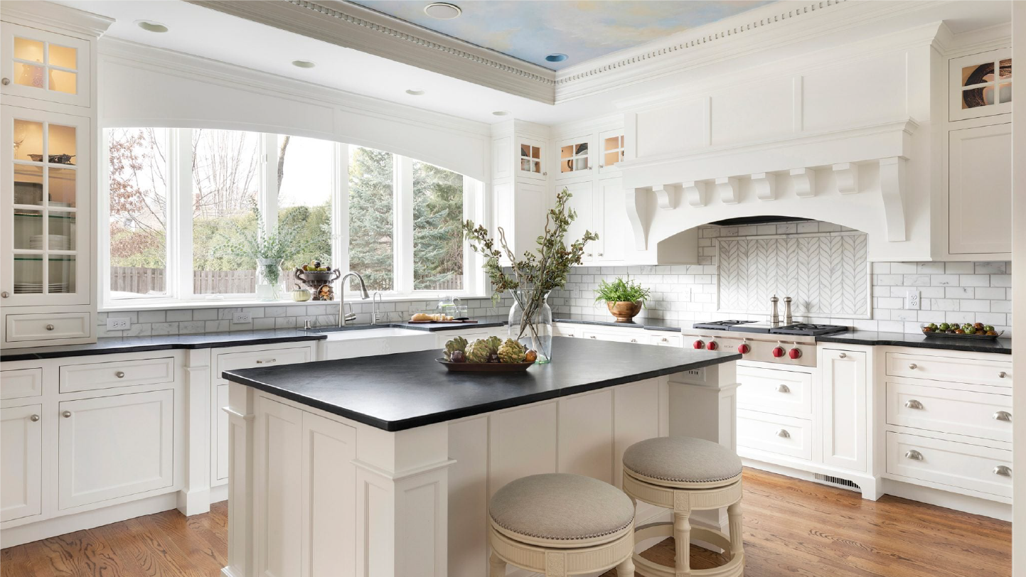 Modern kitchen with a large wooden island, stainless steel refrigerator, oven with striped towel, white cabinets, and pendant lights.