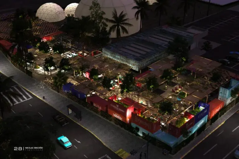 Vista nocturna de un mercado o parque comercial iluminado con contenedores pintados y estructuras de geodomo, rodeado de árboles y palmeras cerca de una carretera.