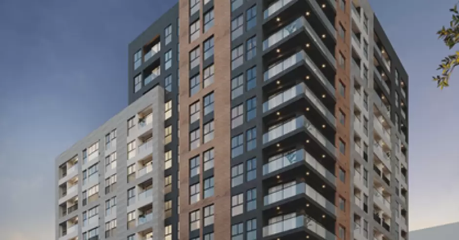 Edificio residencial moderno de varios pisos con balcones y fachadas en tonos grises, marrón y blanco al atardecer.