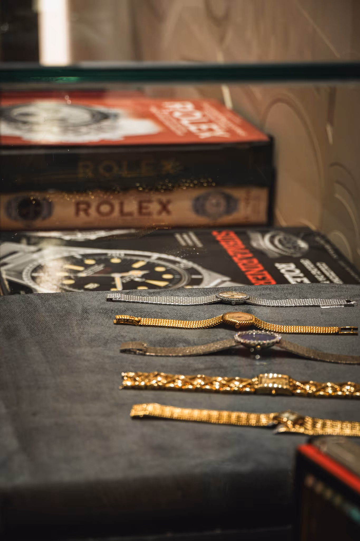 Coleccion de relojes antiguos de oro con libros de coleccion de Rolex de fondo