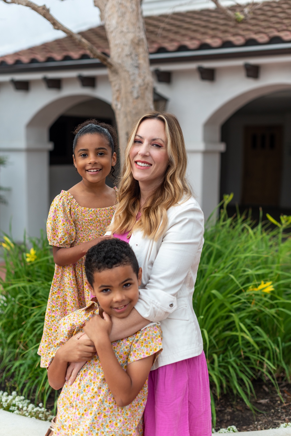 mommy and me outfits 2 | Mommy and Me Outfits by popular LA fashion blog, Posh in Progress: image of a mom and her two kids standing outside and wearing a white blazer, pink dress, nude heel sandals, floral print dress, floral print button up shirt, chambray shorts, gold strap sandals, and blue sneakers. 
