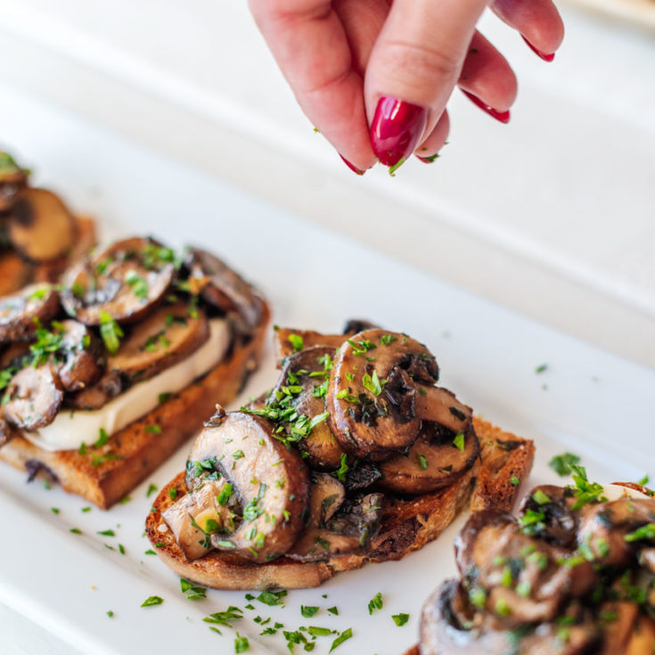 stacey sprinkles parsley on the mushroom Bruschetta
