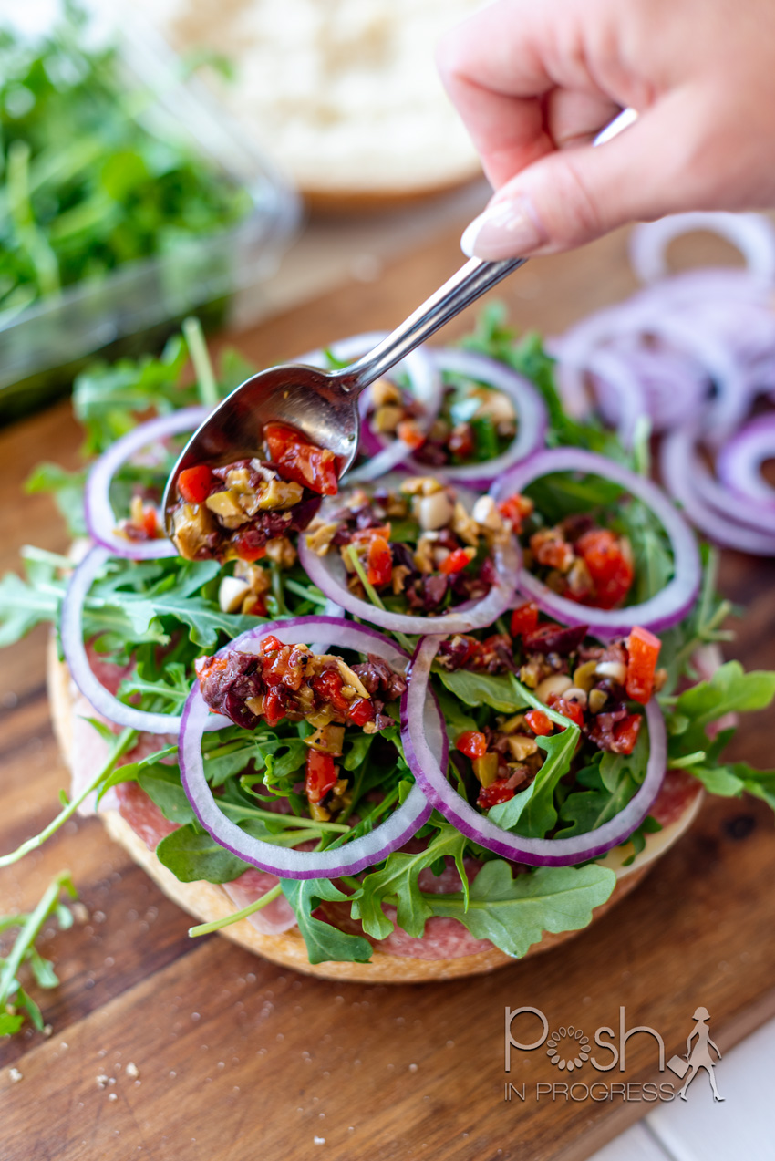 Muffuletta Recipe by popular LA lifestyle blog, Posh in Progress: image of a woman making a muffuletta sandwich. 