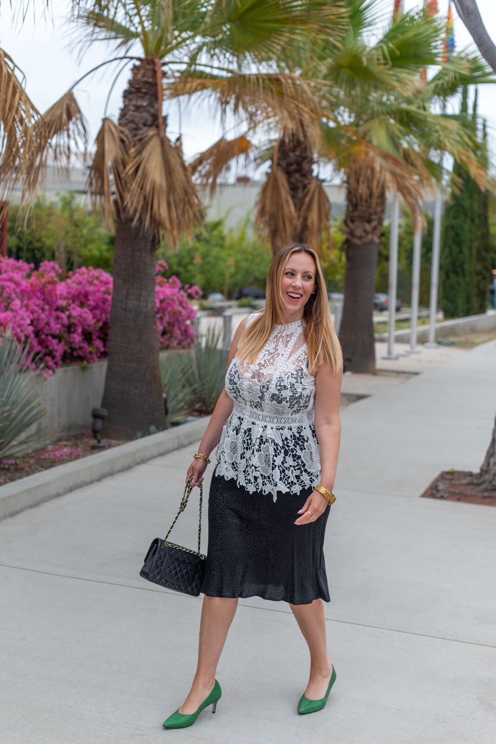 What to Wear by popular LA fashion blog, Posh in Progress: image of a woman wearing a white lace top, black skirt gold watch, gold link bracelet, green heels, and black quilted Chanel bag. 