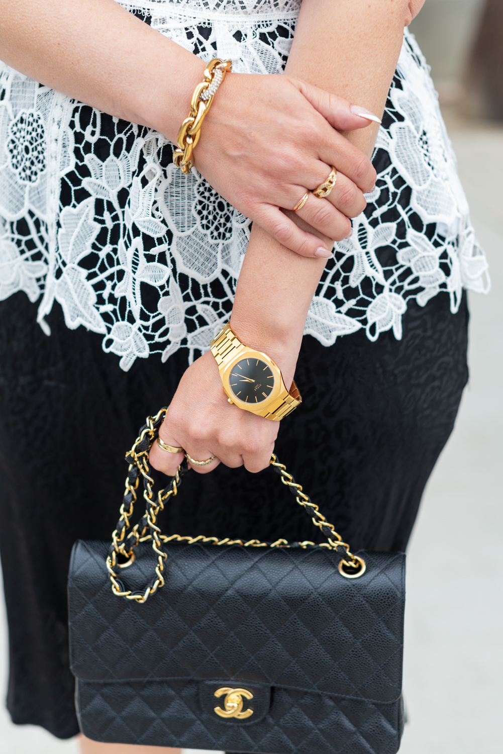 What to Wear by popular LA fashion blog, Posh in Progress: image of a woman wearing a white lace top, black skirt gold watch, gold link bracelet and black quilted Chanel bag. 