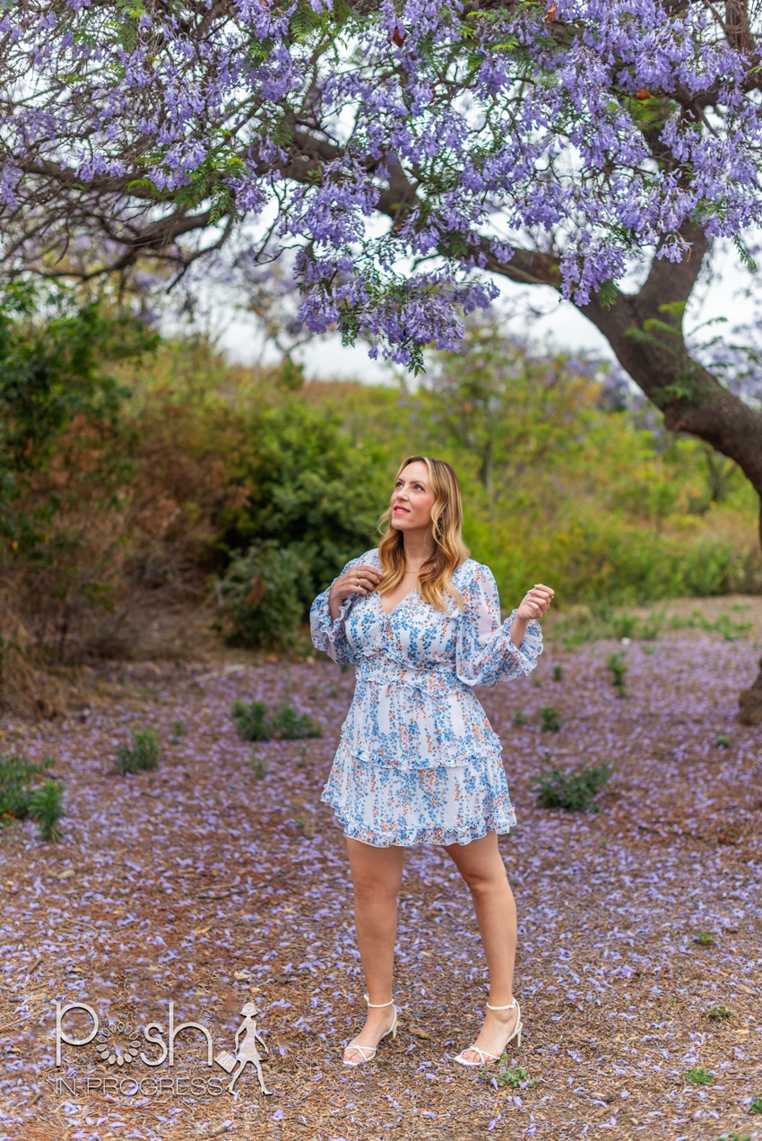 floral backless dress 2 | Backless Dresses by popular LA fashion blog, Posh in Progress: image of a woman standing under a jacaranda tree and wearing a white floral print dress with white heel sandals. 