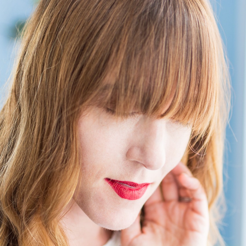 Woman styling her hair while growing out bangs