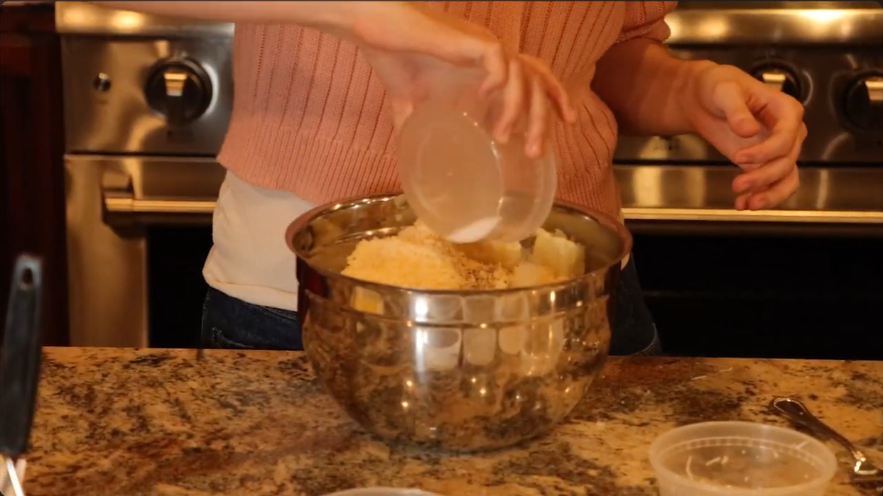 Screenshot of a video made by bryndon, has a girl adding spices and ingredients to a bowl of mashed potatoes.