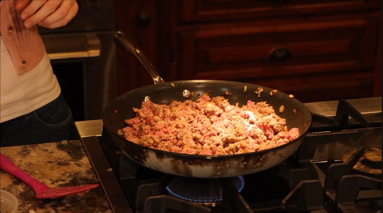 Screenshot of a video made by bryndon, has a close up of a mixture of ground beef and spices cooking on a stove.