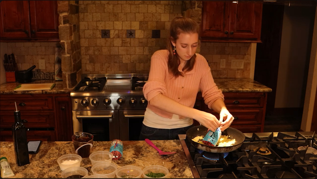 Screenshot of a video made by bryndon, has a girl cooking shepherd's pie on a stove.