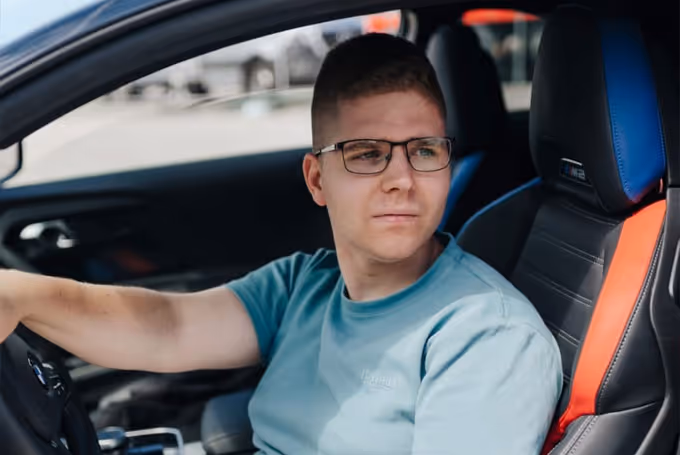 Nicko Bennert sitzend in einem Luxus Auto während einer Fahrzeugüberführung.