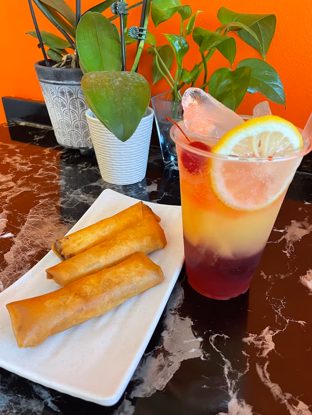 A glass of pink drink with a lemon slice in it.